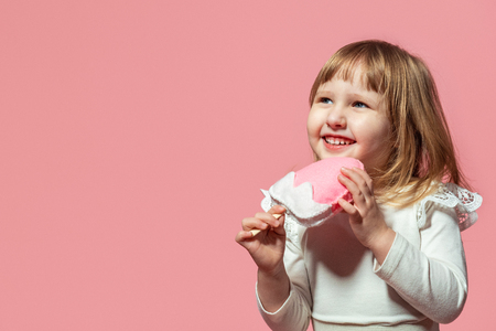 happy kid with ice cream ice cream in hand on a pink coral background. with free text space.の写真素材