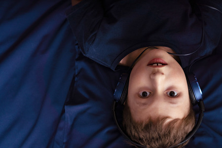 boy listening to music in headphones Lying in bed, view from the top. with free text spaceの写真素材