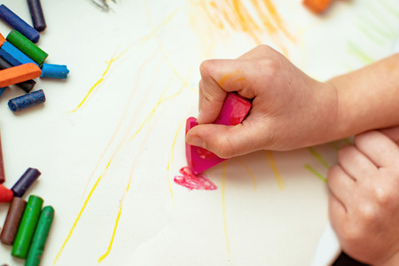 the child draws a flower on paper with wax crayons made with his own handsの写真素材