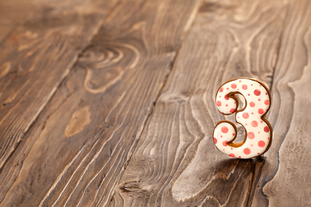 number three on a wooden background. gingerbread with frosting.の写真素材