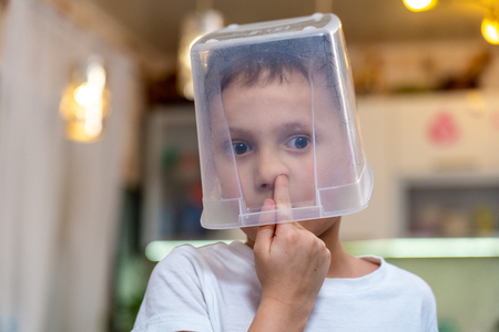 the child picks his finger in the nose in search of snot, hid in a transparent containerの写真素材