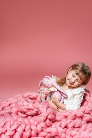 happy baby on pink coral background covered with blanket and Merino. with free text space.の写真素材