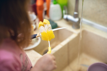 child washing dishes, help in the kitchen, new experiences, receiving skills, dangerous knife in the hands of a childの写真素材