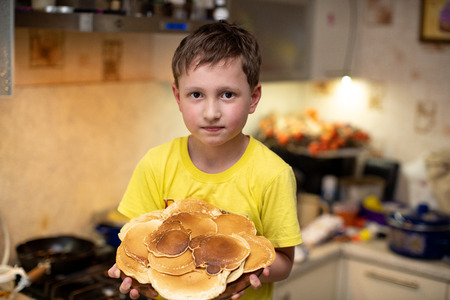 the child is holding a plate of pancakesの写真素材