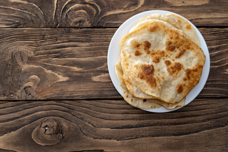on a plate are fried bread cakes, wood textured table view from the top. with free text, copy space,