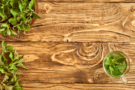 on a wooden background is a glass with brewed young nettles. medicinal broth of nettle. vitamin...