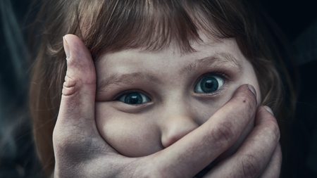A frightened young girl with a grown man's hand covering her mouth. fear and despair in the child's...