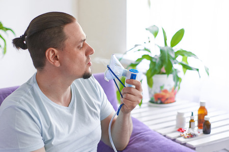 a sick man breathes through an inhaler mask