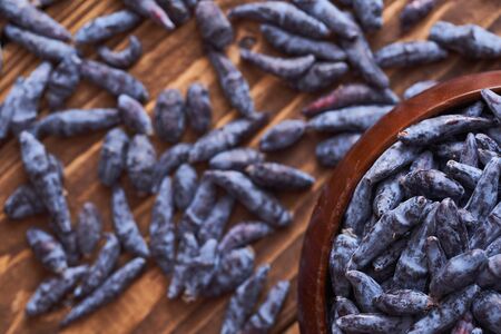 oblong fruit of the honeysuckle berries on wooden background. honeysuckle berries close-upの写真素材