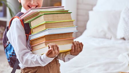 Joyful child holding a stack of textbooks. Selective focus on textbooks. free text, copy space,の写真素材
