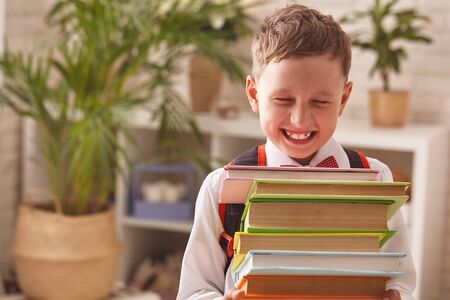boy student holding a large stack of books and smiles happily. free text, copy space,の写真素材