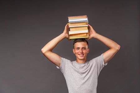 portrait of a student boy with a backpack and a stack of books in his hands on his head. funny...