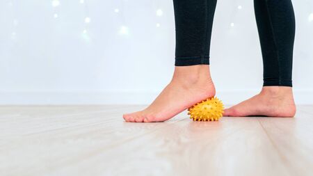 Close-up of a leg in sportswear with a massage ball. Heel pressure on the ball. Training at home. Prevention of foot diseases. The concept of a healthy lifestyle and sports.の写真素材