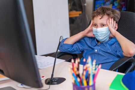 boy with mask on his face is tired distance learning during quarantine covid-19. concept of online...