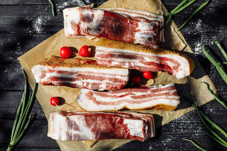 Sliced smoked gammon on a wooden table with addition of fresh herbs and aromatic spices. Natural product from organic farm, produced by traditional methods. High quality photoの写真素材