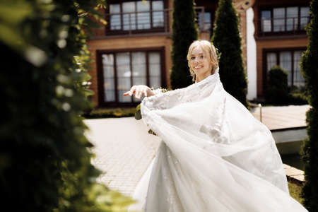 bride in a dress standing in a green garden and holding a wedding bouquet of flowers and greenery. High quality photoの写真素材