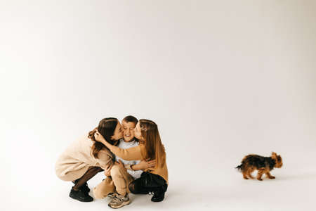 Mom hugs daughter and son on a white background. High quality photo