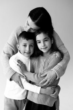 Mom hugs daughter and son on a white background. High quality photoの写真素材
