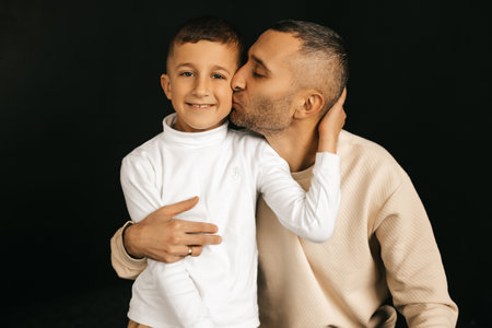 Dad with son on black background, father's love. High quality photo