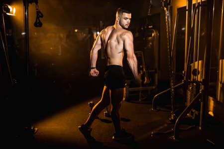 Young man athlete posing in the gym, stimulates to go in for sports. High quality photoの写真素材