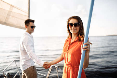 A couple in love on the edge of the yacht hug and hold hands, show love, strong hugs, blue sea, white sailing yacht. Happy valentines day. High quality photoの写真素材