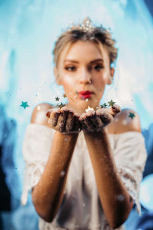 Cute beautiful girl blowing gold stars, stardust from her hands. ... High quality photoの写真素材