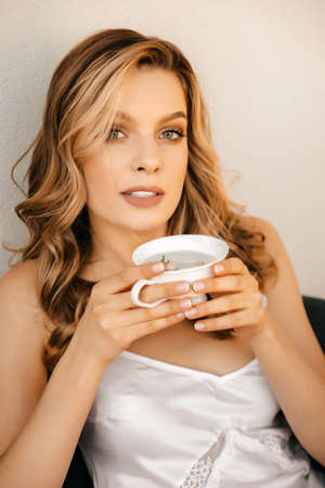 Beautiful blonde woman drinks herbal tea on the balcony of her house, morning of the brideの写真素材