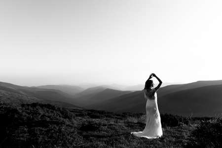 Black and white photo, a beautiful bride in a white wedding dress silhouetted from the rays of the sunの写真素材