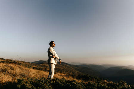 Handsome man in glasses and a light beige suit walks in the mountains. High quality photoの写真素材