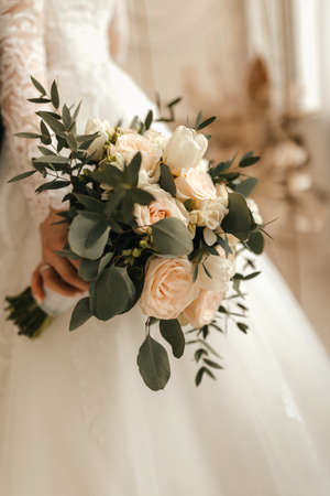 The bride in a white dress holds a beautiful wedding bouquet in her hands. High quality photoの写真素材