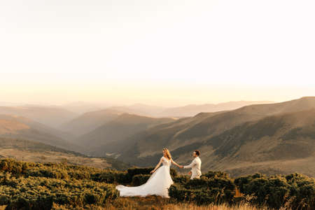 Beautiful young couple in love walk in the mountains by the hand, wedding couple. High quality photoの写真素材