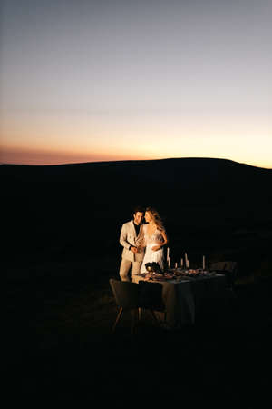 Beautiful young wedding couple smiling, evening wedding in the mountains at a table for two. High quality photoの写真素材