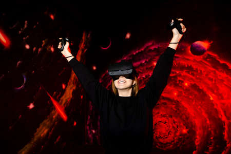 The girl cheerfully and emotionally rejoices at the victory in a video game wearing virtual reality...