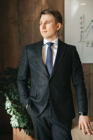 A young successful businessman is standing in a classic suit in the office.の写真素材