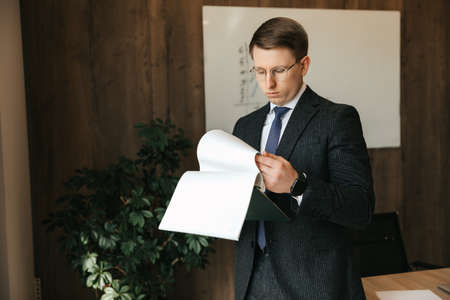 Businessman man in glasses examines documents in the office. High quality photo