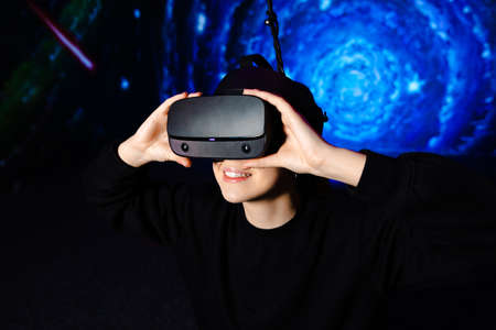 Girl in virtual reality glasses, gaming gadget. Blue background. High quality photo