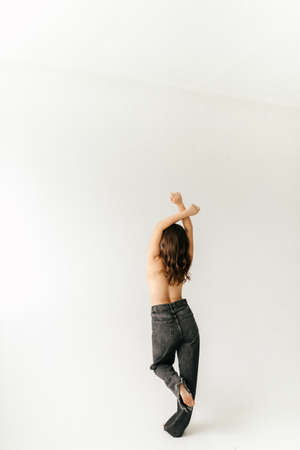 Sexy brunette without a bra with red lipstick on her lips in gray jeansの写真素材