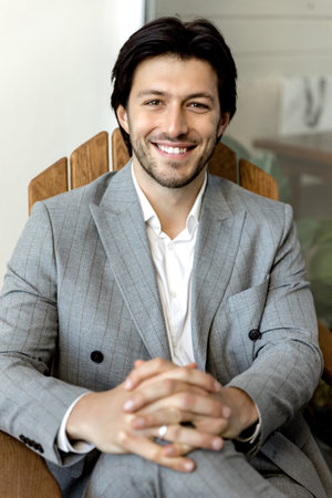 Young successful man smiling and sitting in a light suit. high quality photo