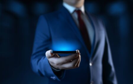 Businessman holding smartphone. Man using phone in officeの写真素材