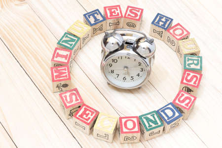 Clock with wood cubes on wooden table words hours,minutes,seconds