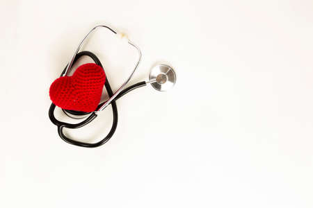 Heart health and prevention concept. Stethoscope and red heart of crochet on white isolated...
