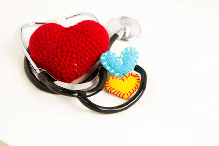Heart health and prevention concept. Stethoscope and red heart of crochet on white isolated...