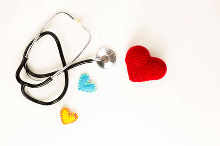 Heart health and prevention concept. Stethoscope and red heart of crochet on white isolated background with space for text.の写真素材
