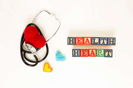 Heart health and prevention concept. Stethoscope and red heart of crochet on white isolated background with space for text.の写真素材