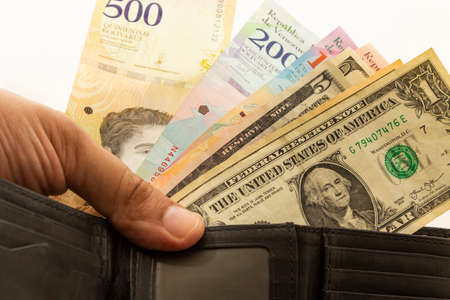 Black leather wallet with Venezuelan money bolivars and US dollar currency.の写真素材