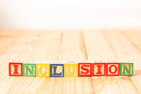 Spectacular wooden cubes with the word INCLUSION on a wooden surface.の写真素材