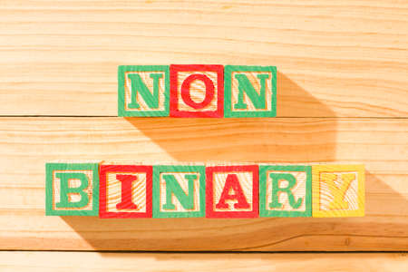 Spectacular wooden cubes with the word NON BINARY on a wooden surface.の写真素材