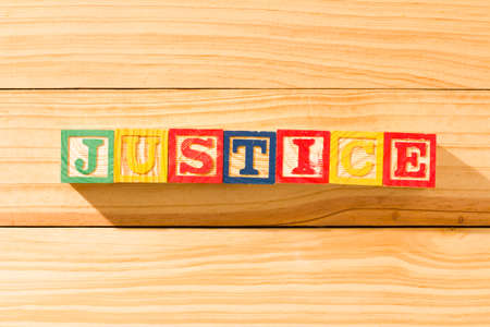 Spectacular wooden cubes with the word JUSTICE on a wooden surface.の写真素材