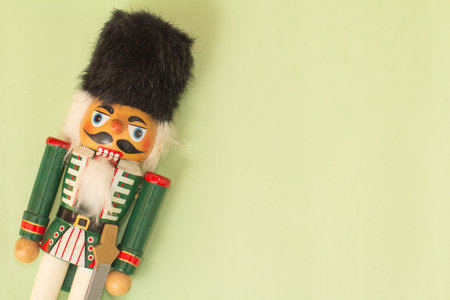 Interesting beautiful christmas nutcracker soldier on green colored paper surface texture with copy spaceの写真素材