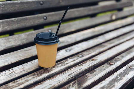 paper cup of coffee on wooden red bench outdoorの写真素材